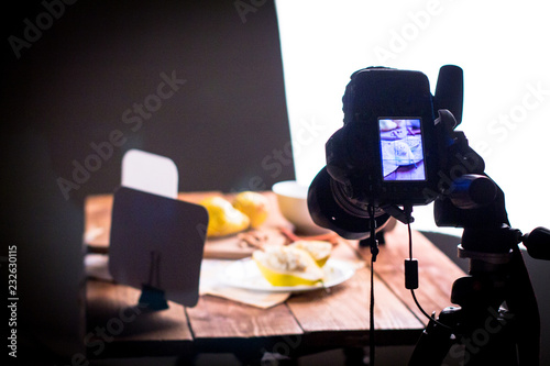 Backstage with a shot of a pear with cottage cheese, nuts, cinnamon and honey on a wooden table subject table. Camera and softboxes.