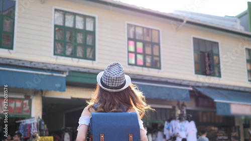 Photography Back side of Young traveling women with backpack in city centre are walking Khaosan Road walking street in evening at Bangkok, Thailand