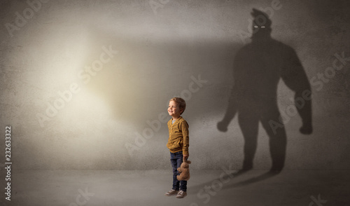 Cute kid in a room with plush on his hand and hero shadow on his background 