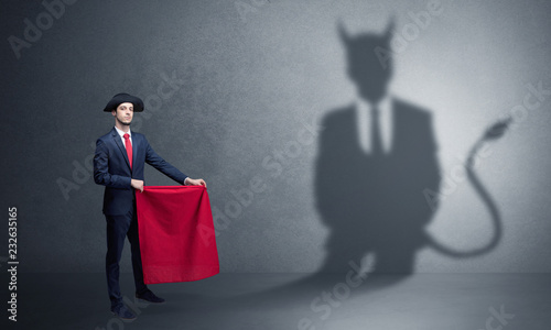 Businessman standing with red cloth in his hand and devil shadow on the background
