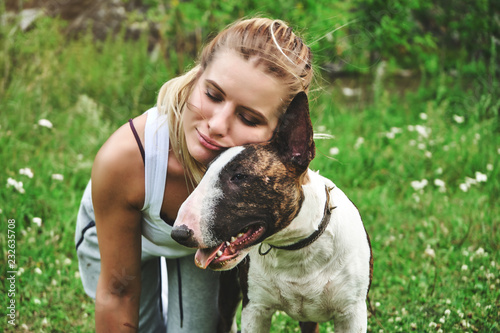 Girl on a green grass with bull terrier photo