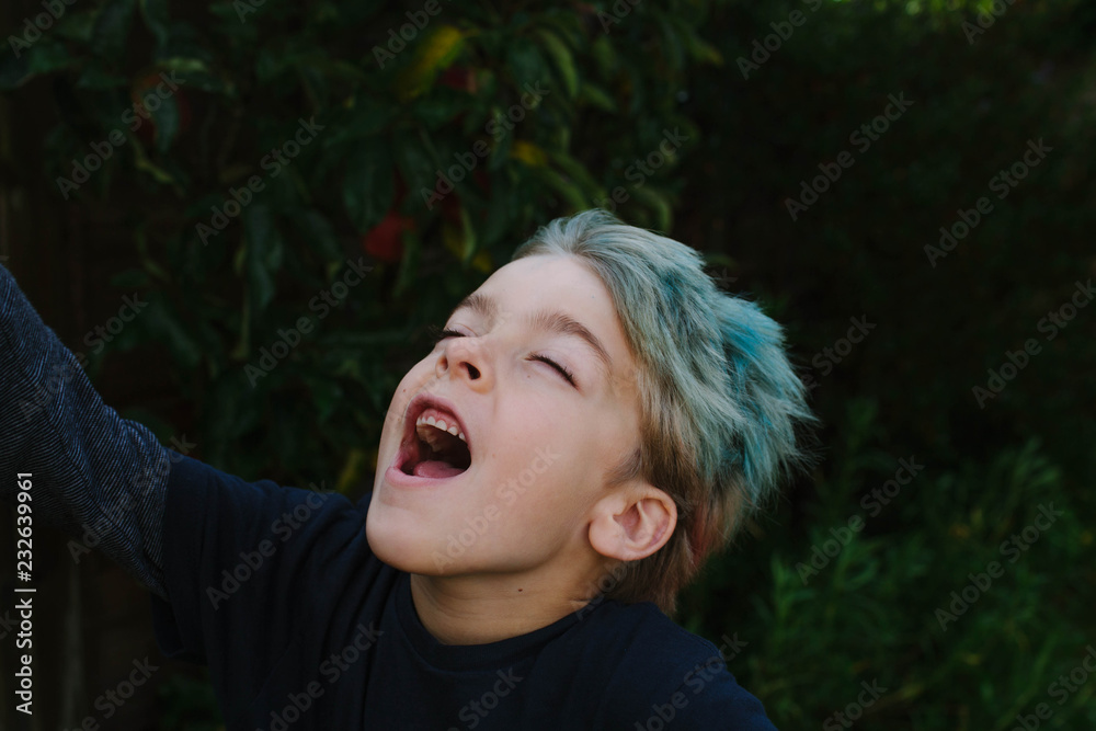 © Stocksy - Young boy with blue hair shouts loudly with his eyes closed. © Stocksy - Young boy with blue hair shouts loudly with his eyes closed.