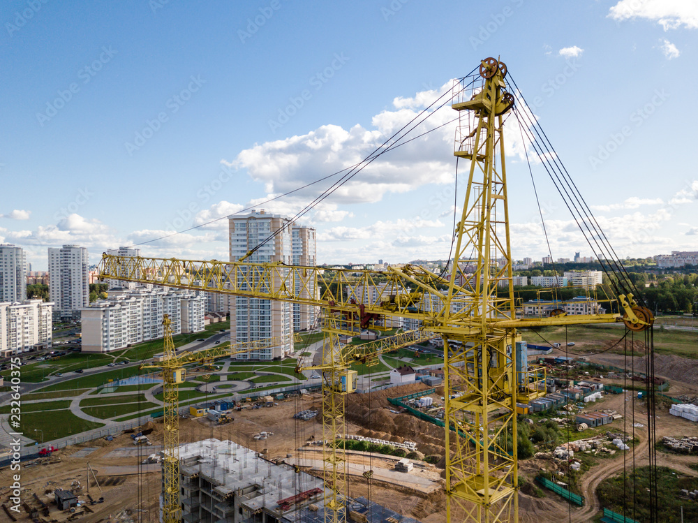 Naklejka premium Aerial drone view Cranes close-up on construction site against blue sky