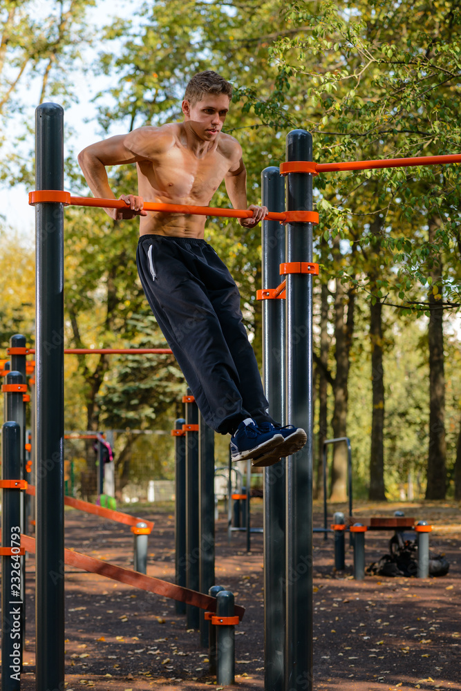 Fototapeta premium Muscular man doing pull-ups on horizontal bar