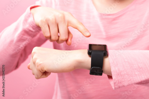 Young woman with a smart watch on a pink background
