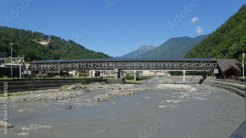 View of the pedestrian bridge over the mountain river Mzymta in Rosa Khutor. Summer, Caucasus, Krasnodar region, Russia. photo