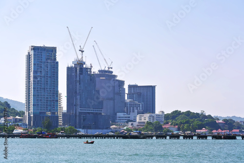 Small Wooden Boat in the Sea with Buildings Under Construction on Background