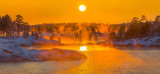 Sunset on the winter lake. Fog from heavy frost, soaring water at sunset. Lake in the winter at sunset in the bitter cold. Ladoga granite islands, skerries.