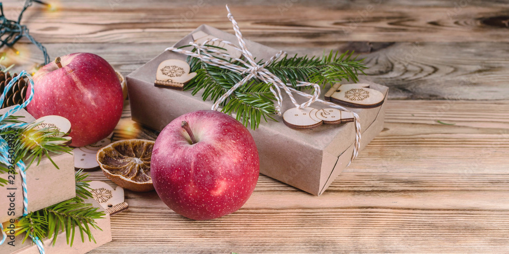Web banner Christmas background. Red apples, gifts, fir branches and cones on a wooden background