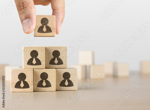 Hand arranging wooden blocks stacking as a pyramid staircase on white background. Human resources management, recruitment or corporate hierarchy concept.