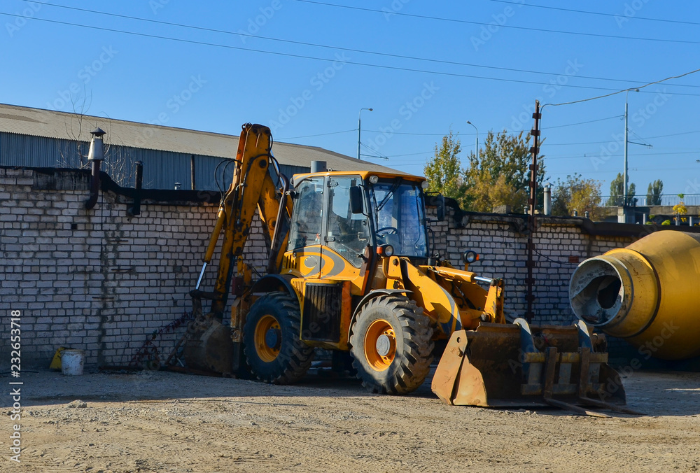 Yellow tractor on the construction site with iron bucket