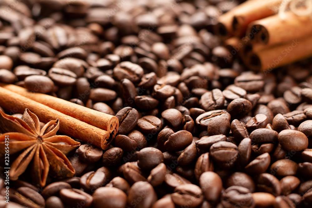 A few sticks of natural fragrant brown cinnamon and anise star are spread out on freshly roasted coffee beans. Photo of coffee beans, cinnamon and anise in backlight. A few sticks of natural fragrant brown cinnamon and anise star are spread out on freshly roasted coffee beans. Photo of coffee beans, cinnamon and anise in backlight.
