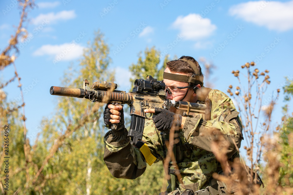 special forces, soldier assault rifle with silencer, optical sight. behind cover waiting in ambush