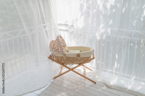 Retro baby crib on terrace rounded with curtain at sunny day