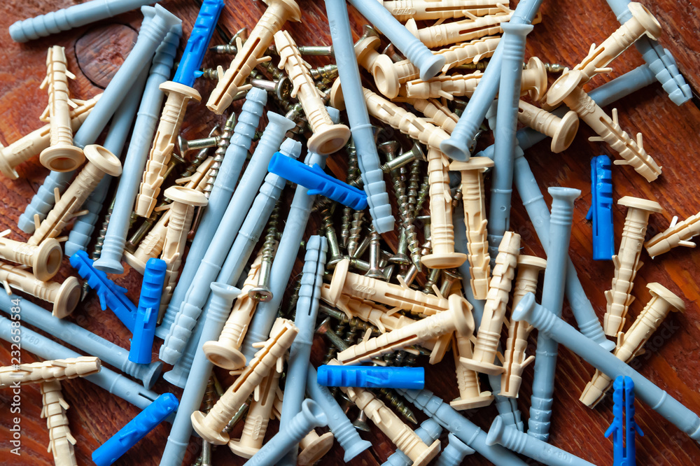 Screws and plastic dowels on a wooden background. Selective focus. Screws and plastic dowels on a wooden background. Selective focus.