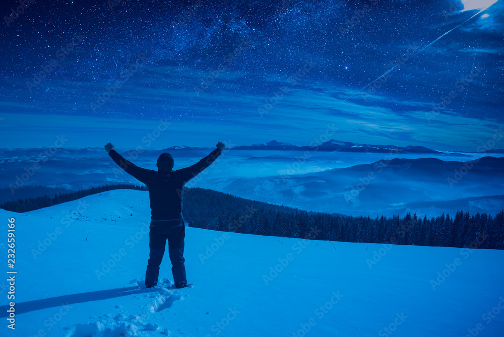 Hiker with raised hands standing on a snowy hill Hiker with raised hands standing on a snowy hill