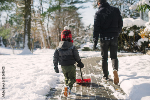 Little kid shoveling snow with dad
