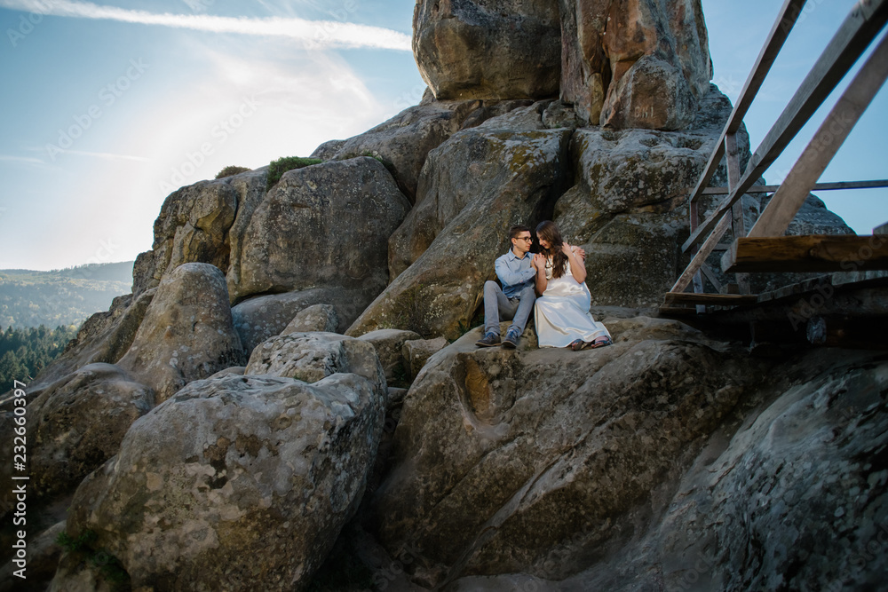 Romantic summer love story on a sunset in mountains. Young girl and boy in love. pregnant women