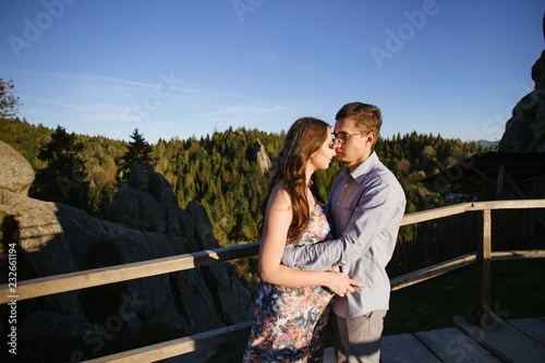 Romantic summer love story on a sunset in mountains. Young girl and boy in love. pregnant women