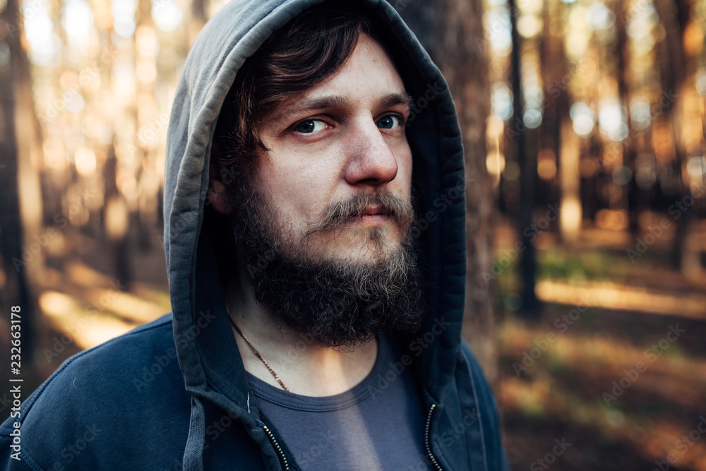 close up portrait of a bearded hipster tourist in gray hood man in the sunlight woods forest close up portrait of a bearded hipster tourist in gray hood man in the sunlight woods forest