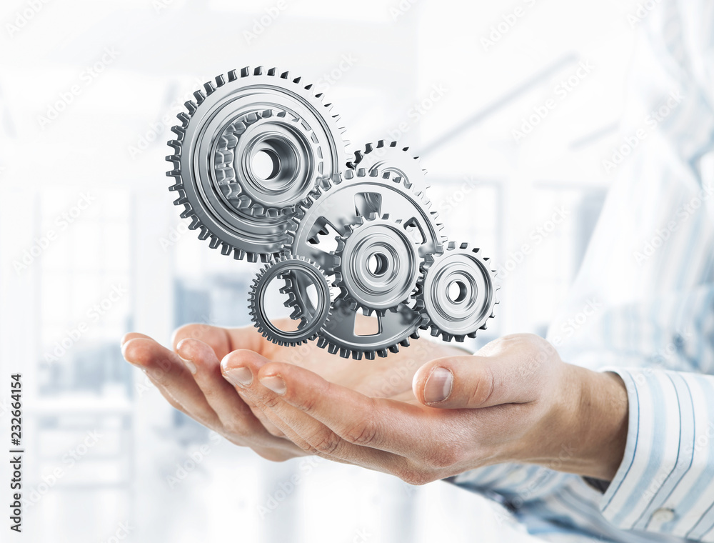 Engine mechanism in male ahnds as symbol for cooperation or team Engine mechanism in male ahnds as symbol for cooperation or team