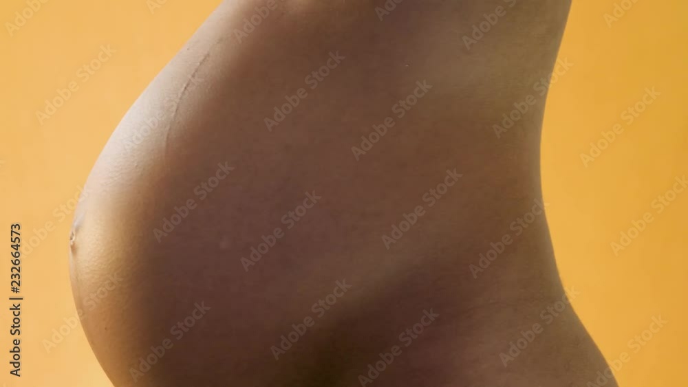 Belly of pregnant woman in yellow background rotating 360 degrees. Presentation of pregnant woman's belly.