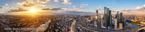 high-rise buildings and transport of metropolis  traffic and blurry lights of cars on multi-lane highways and road junction at sunset in Moscow