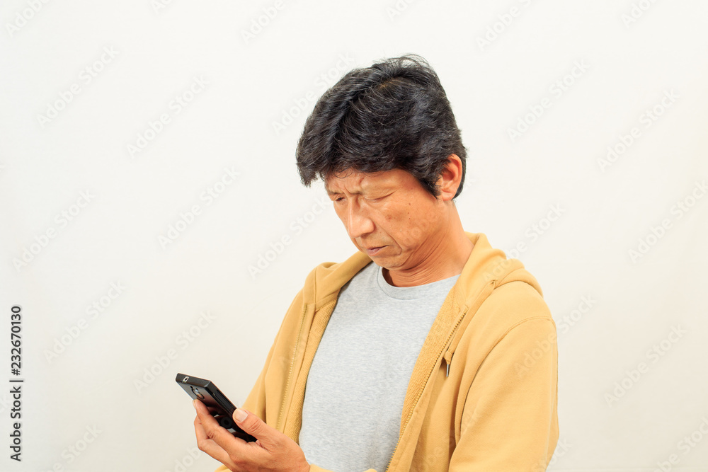 スマートフォンに目を凝らす中年男性 スマートフォンに目を凝らす中年男性