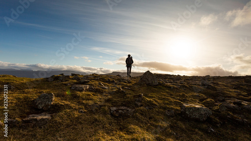 Man exploring the highlands of Faroe Islands on a beautiful sunny day of summer
