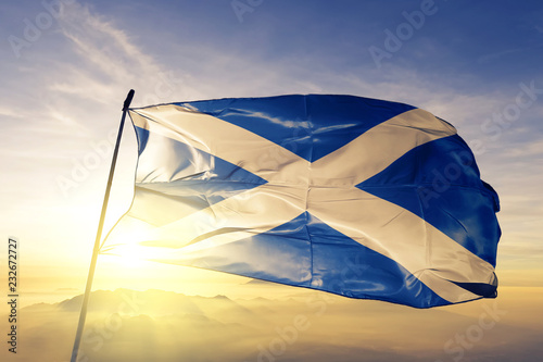 Scotland scottish flag textile cloth fabric waving on the top sunrise mist fog