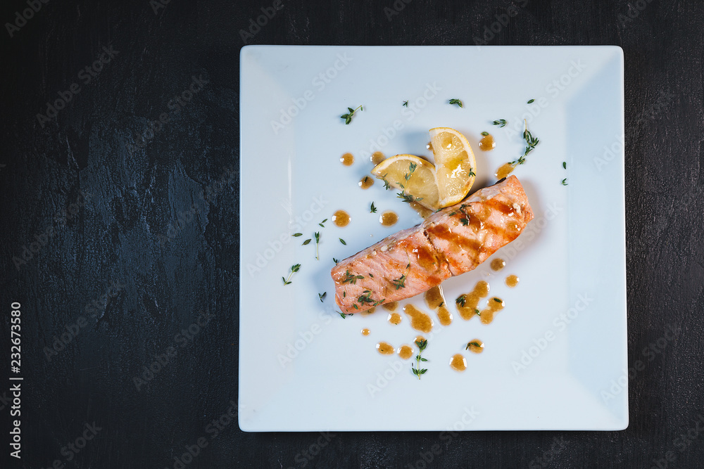 Tasty fresh salmon in white plate on black stone table background Tasty fresh salmon in white plate on black stone table background