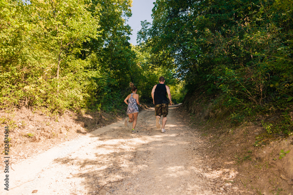 Athletic couple running together on forest trail Athletic couple running together on forest trail