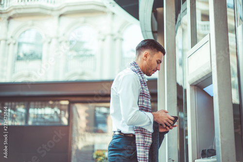 Handsome businessman standing next to ATM Free Download Handsome businessman standing next to ATM - GFXLoad