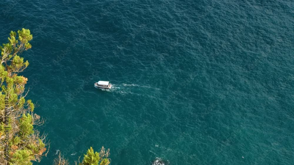 A small tourist motor ship sails on the sea near the shore. A small tourist motor ship sails on the sea near the shore.