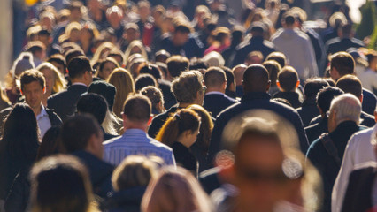 Crowd of people walking busy city street backlit