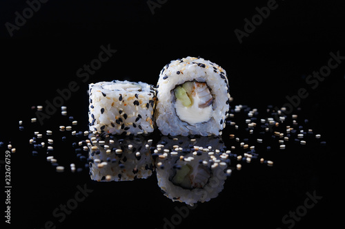 delicious sushi roll with fish and sesame on a black background with reflection Menu and restaurant concept