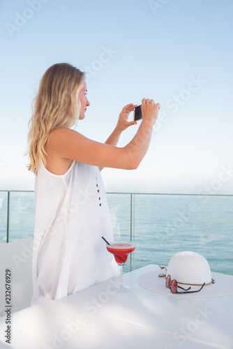 Woman taking a picture of the sea with her smartphone photo