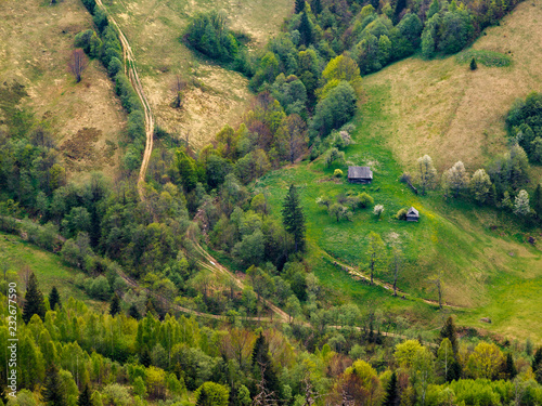 Looking down from the mountain to the small farm house, the forest and lines of roads