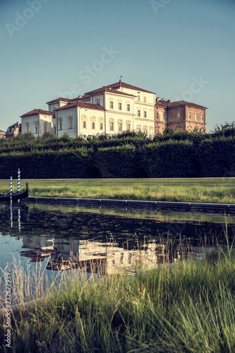 Palace and gardens of Reggia di Venaria near Turin, Italy, reflecting in water pond in a sunny summer day