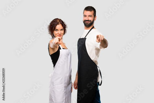 Couple of cooks points finger at you with a confident expression on grey background