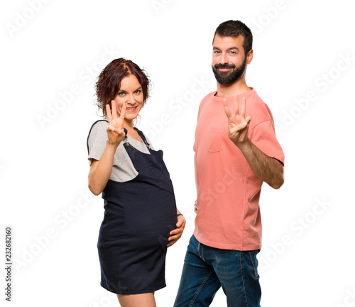 Couple with pregnant woman happy and counting three with fingers on isolated white background