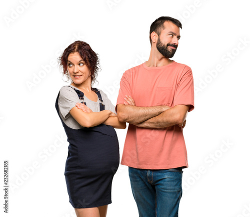 Couple with pregnant woman looking over the shoulder with a smile on isolated white background