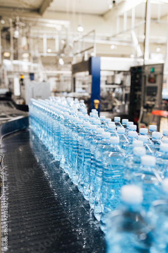 Bottling plant - Water bottling line for processing and bottling carbonated water into blue bottles. Selective focus.