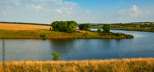 Fototapeta Naklejka Na Ścianę i Meble -  Sunny summer landscape with river,green hills and trees growing along the riverbank.