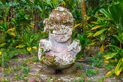 Smiling tiki. Carved stone tiki - Polynesian sacred idol statue hidden in jungle. Raivavae island, Astral islands (Tubuai), French Polynesia, Oceania photo
