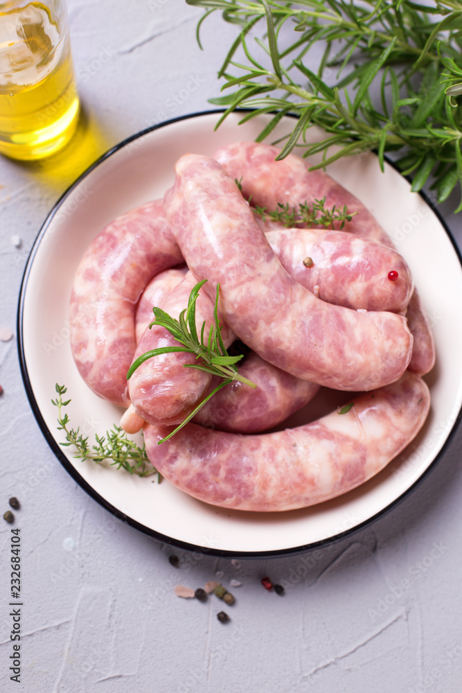 Fresh homemade raw sausages on plate on grey textured background. Fresh homemade raw sausages on plate on grey textured background.