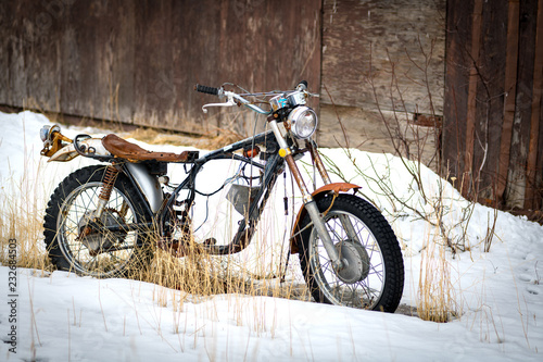 Old antique motorcycle parked in the snow winter time outside