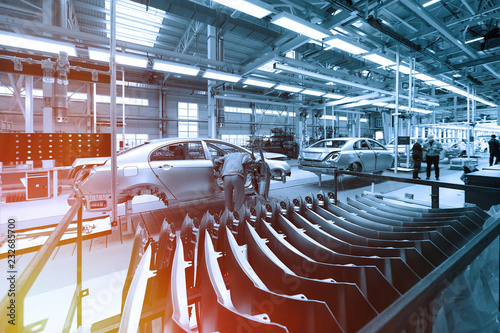 Worker looks into car body on production line. Factory for production of cars in blue. Modern automotive industry. Blue tone photo