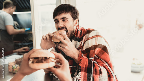 Young Couple in Checkered Plaids Eating Burgers.