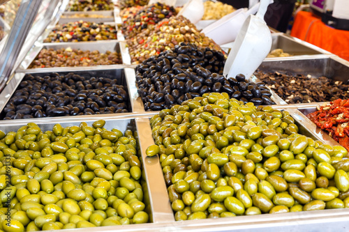 Assortment of different marinated olives for sale on a shop window.